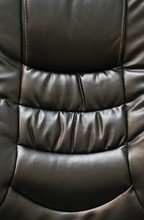 Back Of A Black Leather Chair Emphasizing The Glossy Finish, Shadows, Textures And Seams In Vertical Format. Showing Only Partial Areas For Abstract Purposes.