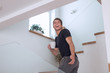© ASDF - smiling guy with smartphone standing on the stairs in his house