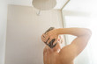 © Maridav - Man taking a shower washing hair under water falling from rain showerhead in luxury walk-in bath. Showering young person at home lifestyle. Body care morning routine in sunlight.