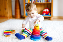 Adorable Cute Beautiful Little Baby Girl Playing With Educational Toys At Home Or Nursery. Happy Healthy Child Having Fun With Colorful Wooden Rainboy Toy Pyramid. Kid Learning Different Skills