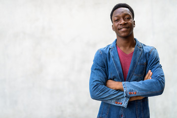 Wall Mural - Young handsome African man wearing denim jacket against concrete