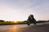 Fast motorcycle drive on asphalt road at sunset.