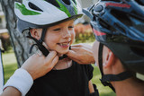 Loving mother helping her daughter to put on bicycle helmet