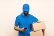 © luismolinero - Delivery man with beard over isolated background sending a message with the mobile
