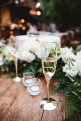 Wall Mural - Vertical selective focus shot of a glass of champagne on a wooden surface at a wedding