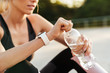 © Drobot Dean - Image of sportswoman in tracksuit drinking water during workout outdoors