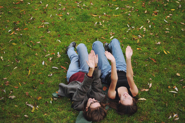 Two girls in blue jeans are lying on the grass