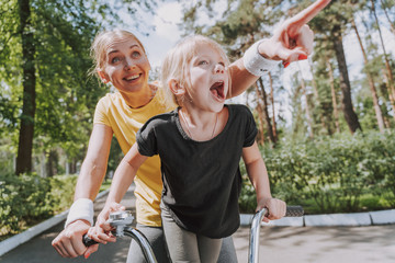 Wall Mural - Cheerful woman riding bike with her daughter