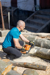 Wall Mural - Man cut with saw. Dust and movements. Woodcutter saws tree with chainsaw on sawmill. lumberjack