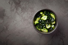 Wakame Salad Raw Seaweed With Cucumber Slices And Sesame In Bowl On Dark Gray Background Top View With Copy Space.Japanese Cuisine.Organic Product.Raw,vegan,vegetarian Food.Horizontal Orientation