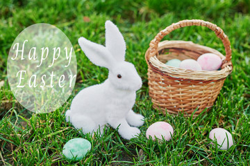 Easter bunny on spring green grass. Cute rabbit. Easter egg hunt with pet bunny. Happy Easter greeting card with copyspace. Easter greeting card template. Rabbit and eggs on grass.