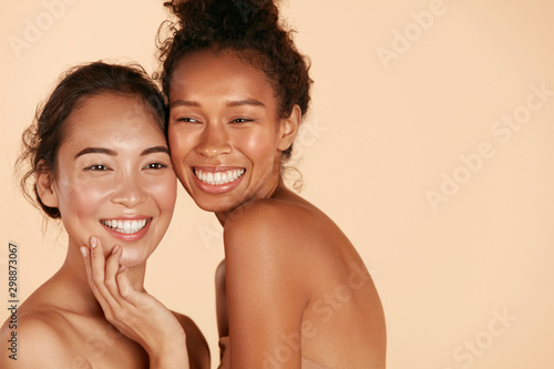 Zdjęcie: Beauty. Smiling women with perfect face skin and natural makeup portrait. Beautiful happy asian and african girl models with different types of skin on beige background. Spa skin care concept Beauty. Smiling women with perfect face skin and natural makeup portrait. Beautiful happy asian and african girl models with different types of skin on beige background. Spa skin care concept