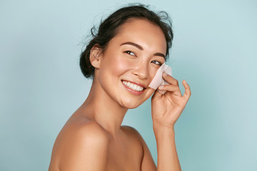 Wall Mural - face skin care. smiling woman using facial oil blotting paper portrait. closeup of beautiful happy a