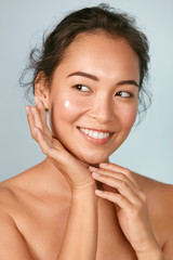 face skin care. woman applying cosmetic cream on clean hydrated skin portrait. beautiful happy smili