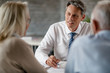 © Drazen - Insurance agent taking notes while talking to senior couple on a meeting.
