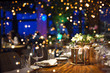 © IrynaV - Blurred party background with served table with bouquet of flowers and people sitting at restaurant, bar or night club with colorful lights bokeh.