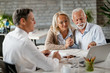 © Drazen - happy senior couple using computer while having a meeting with real estate agent.