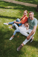 Beautiful happy family sitting on green grass