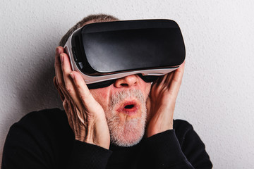 Wall Mural - Portrait of a scared senior man with VR goggles in a studio.