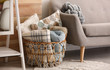 Basket with blankets and pillows near sofa indoors