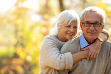 Elderly Couple Embracing In Autumn Park 