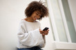 © mimagephotos - smiling african american woman looking at mobile phone outside