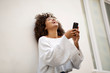 © mimagephotos - young african american woman laughing with mobile phone