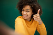 © mimagephotos - happy african american young woman taking selfie with thumbs up sign