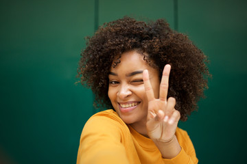 Wall Mural - smiling african american young woman taking selfie with peace hand sign