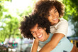 © mimagephotos - Close up happy afro man giving piggyback to smiling girlfriend outside