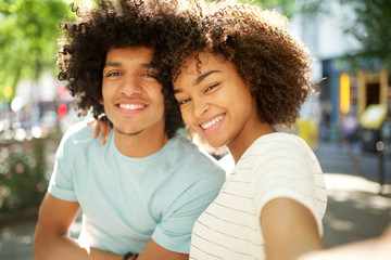 happy afro couple taking selfie together outside in city