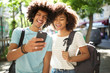 © mimagephotos - happy young african american students looking at cellphone