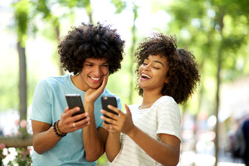 Wall Mural - young afro man with mobile phone looking at happy african american woman cellphone