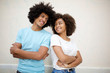 © mimagephotos - smiling african american couple against white background with arms crossed