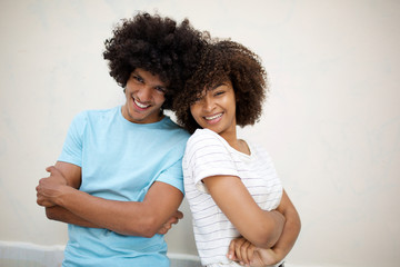 happy african american couple with arms crossed by white wall