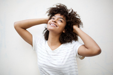 Wall Mural - cheerful young african american woman laughing with hand in hair and looking up by white background