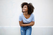© mimagephotos - happy young african american woman smiling with arms crossed and looking away by white background