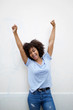 © mimagephotos - cheerful young african american woman with arms raised