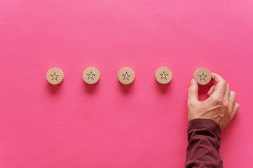 Wall Mural - male hand placing five wooden cut circles with star shape on them in a row