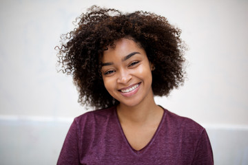 Wall Mural - front horizontal portrait of happy young african american woman with curly hair by white wall
