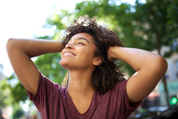 Wall Mural - smiling african american girl with hands in curly hair looking away