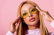 © LIGHTFIELD STUDIOS - portrait of stylish, blonde african american woman touching glasses isolated on pink, fashion doll concept