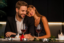 Excited Loving Couple Celebrating Special Event With Wine And Candles , Having Dinner Together