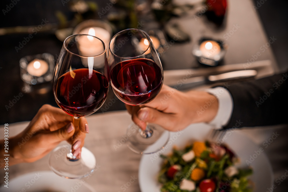 Close up of young couple toasting with glasses of red wine at restaurant - obrazy, fototapety, plakaty 