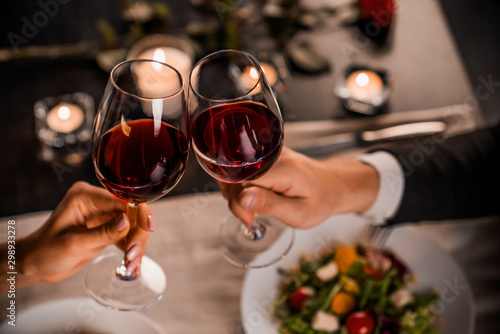 Fotografía Close up of young couple toasting with glasses of red wine at restaurant