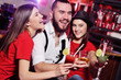 © Evgeniy Kalinovskiy - group of friends-young guy and two cute girls having fun at a party holding cocktails