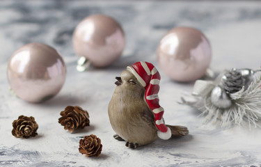 Little winter bird toy in Santa hat on marble background, Christmas composition