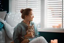 Young Woman With Cute Cat At Home. Cozy Winter