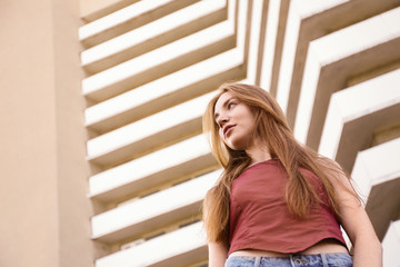 Poster - Beautiful young woman at modern building, low angle view