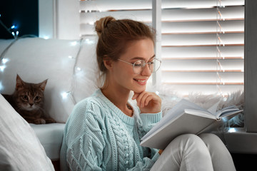 Sticker - Young woman reading book at home. Cozy winter